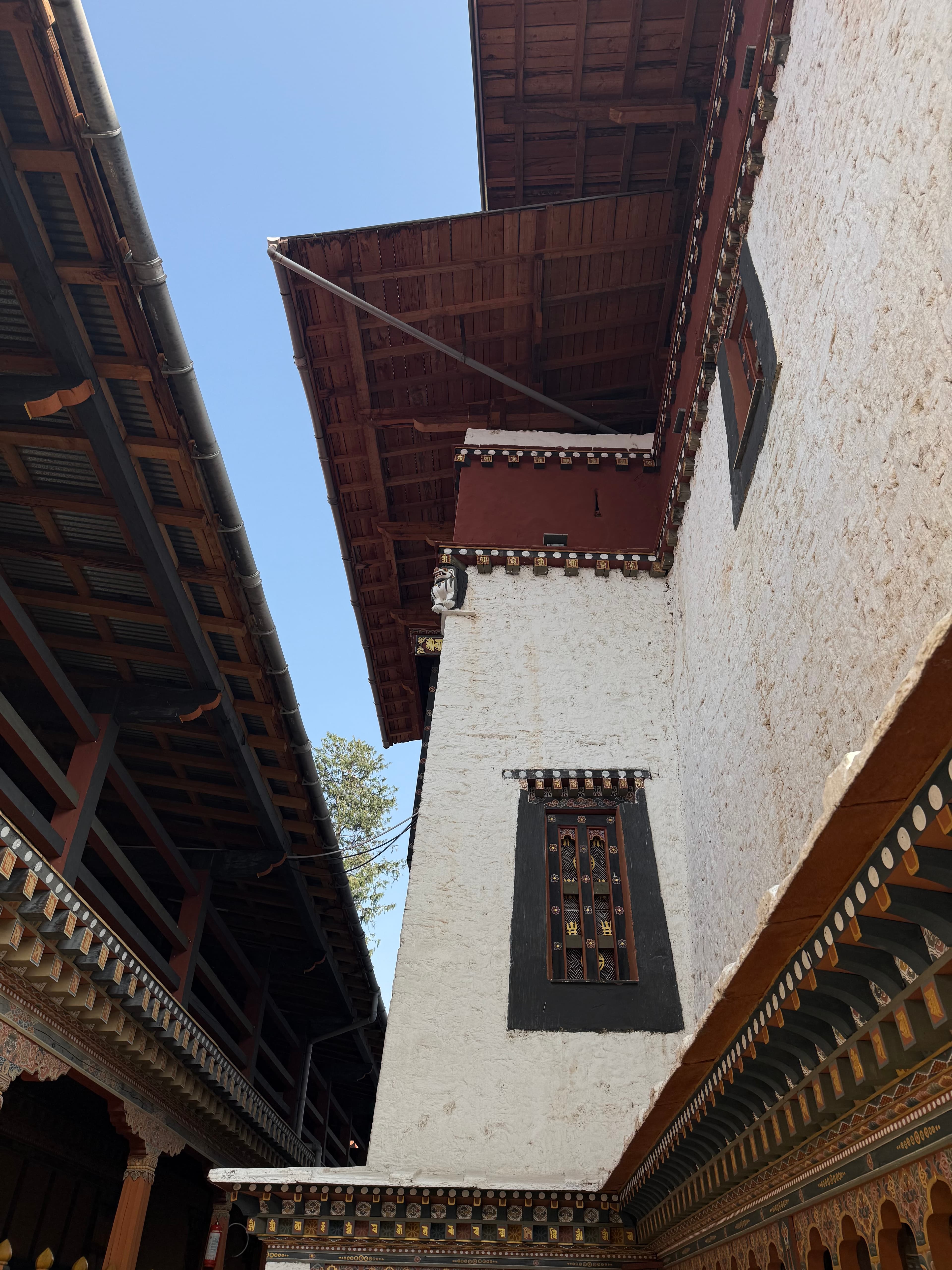 Looking straight up at the painted eaves and white walls of traditional architecture.